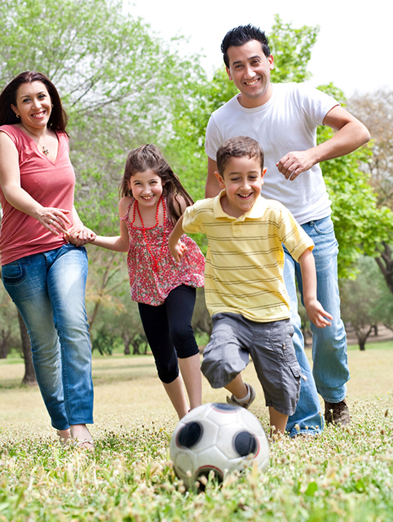 hispanic family playing soccer in a field